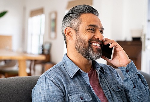Man smiling while talking on phone at home