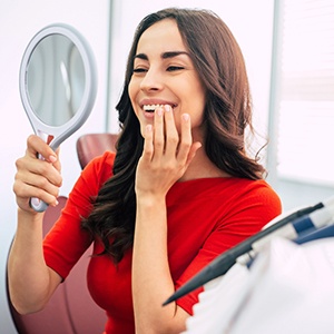 Woman smiling at reflection in handheld mirror