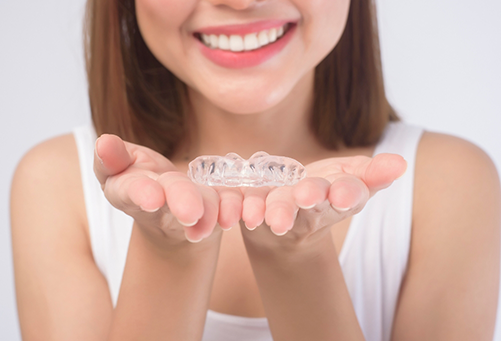 Close up of woman holding clear aligner in palms