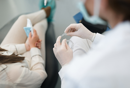 Dentist showing clear aligners to dental patient in chair