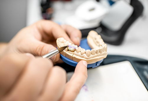 Using brush on dental crown attached to model of teeth
