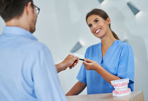 Female dental team member taking credit card from patient