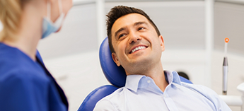 Male dental patient smiling at female dentist