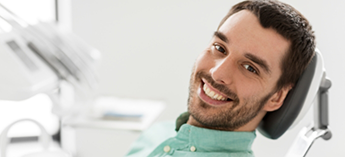 Male patient sitting back in dental chair smiling