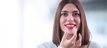 Smiling woman about to put in clear aligner