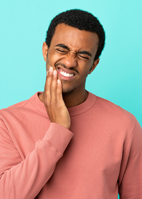 Man in peach colored shirt rubbing jaw in pain