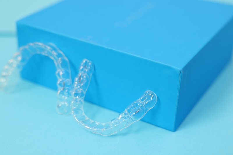 A close-up of mail-in clear aligners against a blue background
